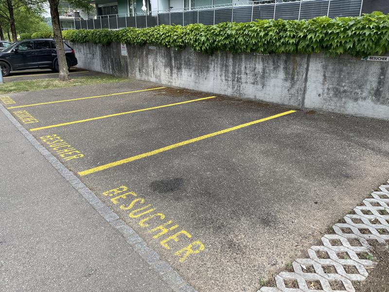 Parkeerplaats met gele lijnen en de tekst BESUCHER op het asfalt.