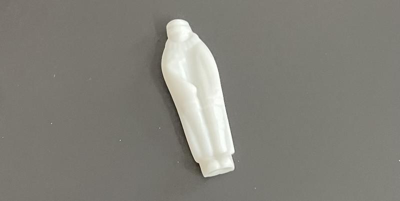 Een ingezoomde foto van een klein wit plastic figuurtje op een grijze tafel. Het figuurtje heeft een mantel aan, maar is niet overduidelijk een koning.