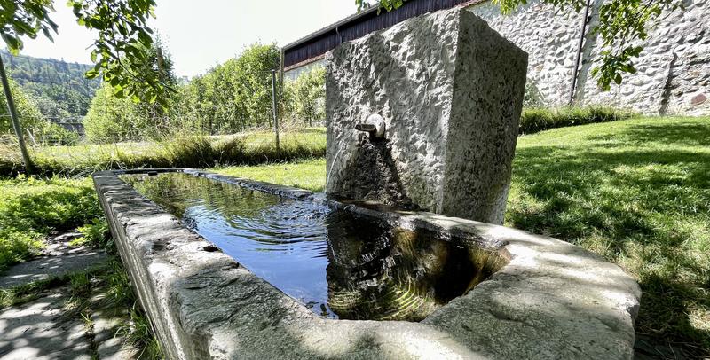 Betonnen drinkfontein met een waterstraal dat in een grote bak wordt verzameld.