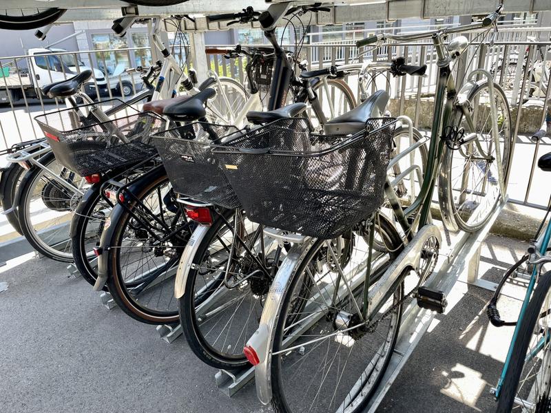 Fietsen geparkeerd in een fietsenrek, met vooraanzicht van een fiets met een zwarte mand.