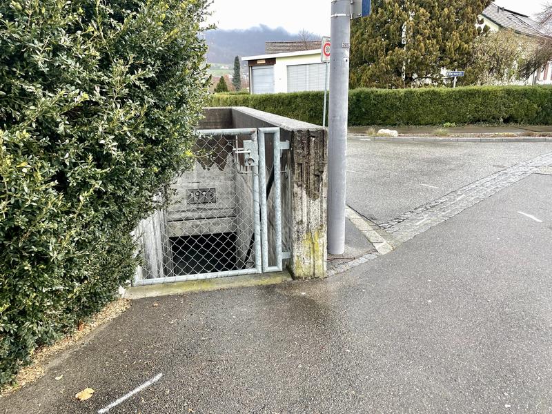 Een trap naar beneden omgeven door een hekwerk, gelegen aan de rand van een trottoir naast een straat.