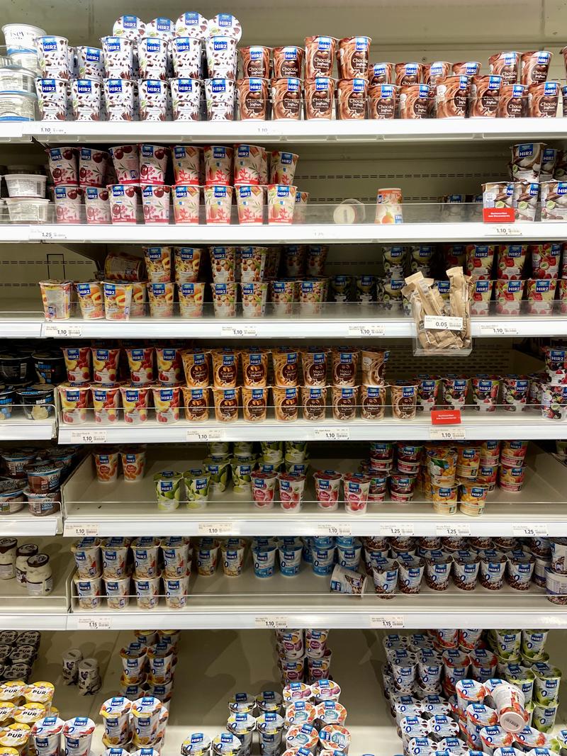 Supermarkt schap gevuld met verschillende soorten yoghurtbekers in diverse smaken en merken.